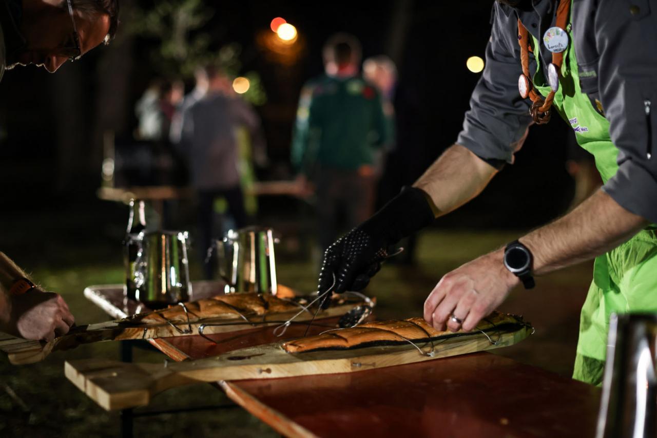 En plein air, un Scout prépare du saumon au feu de bois