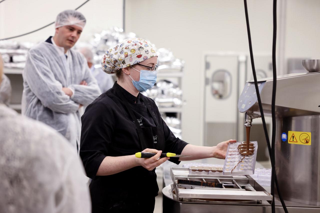 Vue sur une employée en train de remplir des coques de chocolat