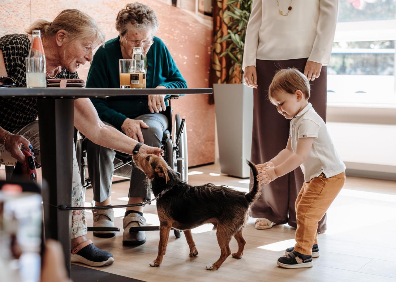 Le Prince Charles et une résident jouent avec un chien