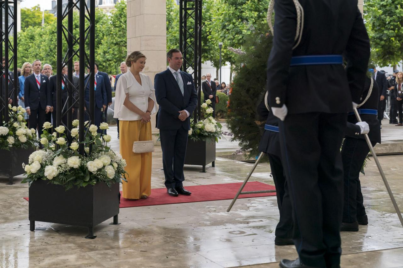 Le Couple héritier devant le monument aux Morts après avoir déposé une gerbe de fleurs