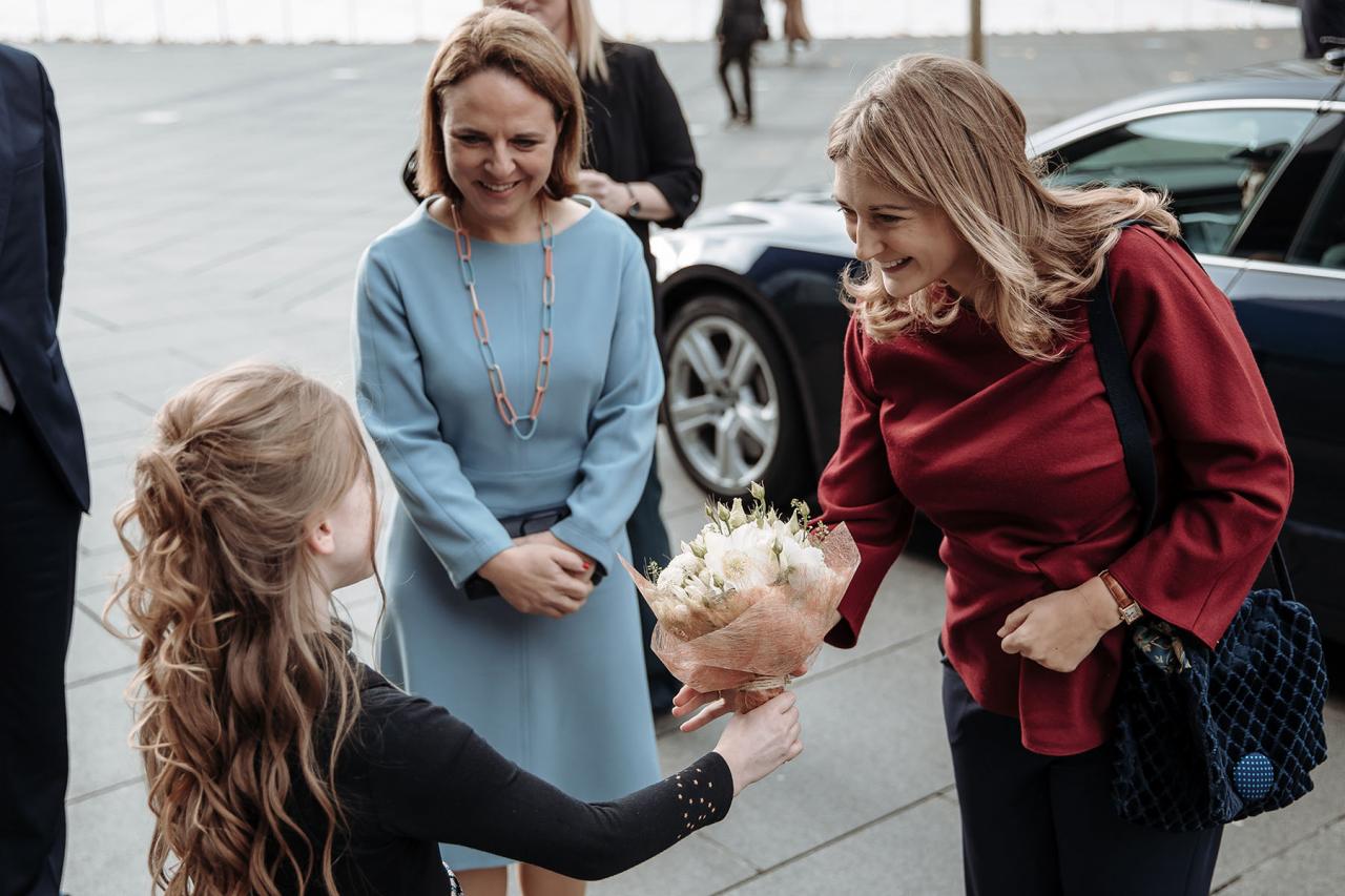 La Princesse est accueillie par une jeune fille avec un bouquet de fleurs