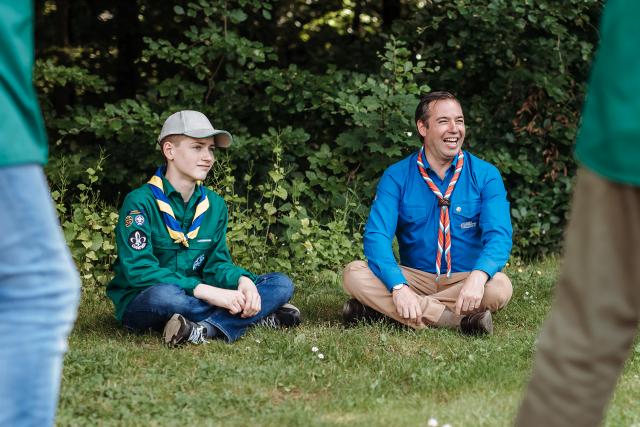 Le Prince Héritier est assis par terre avec un jeune Scout