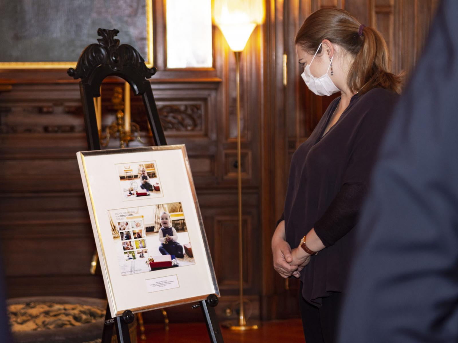 La Princesse Stéphanie examine le cadre le cadre souvenir "Premier anniversaire du Prince Charles"