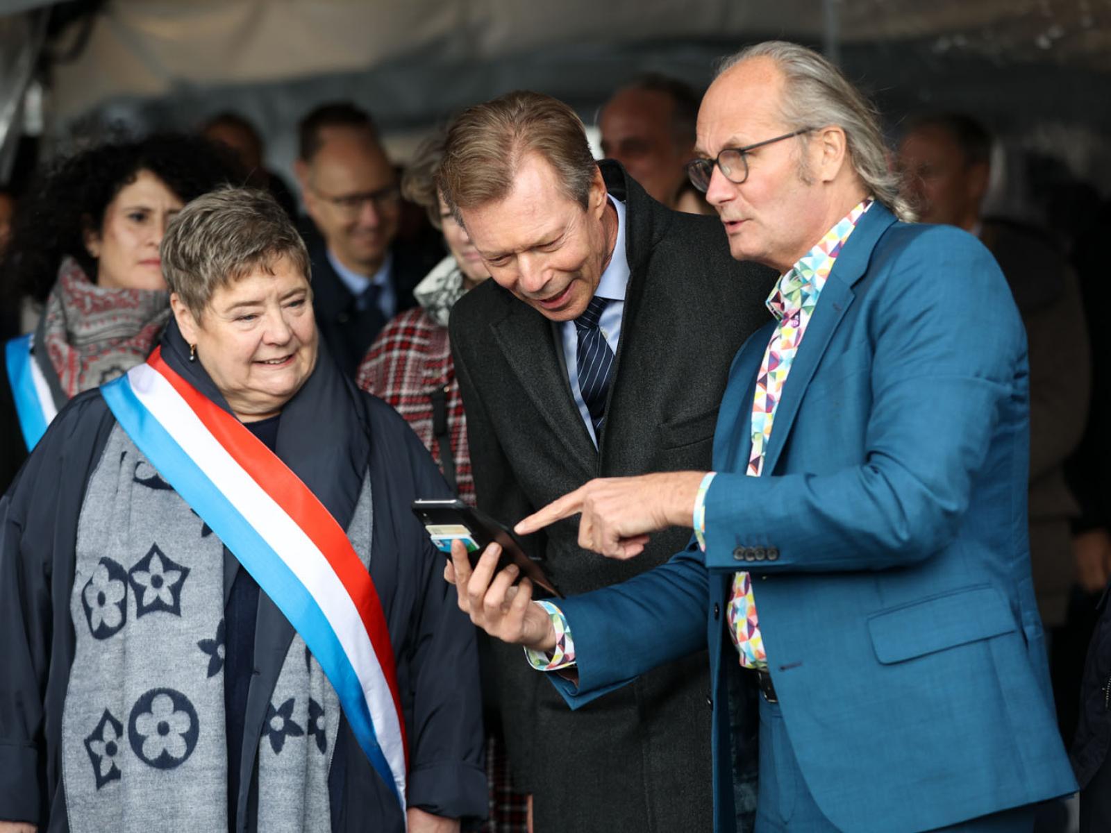Le ministre de l'Énergie montre au Grand-Duc une information sur son téléphone