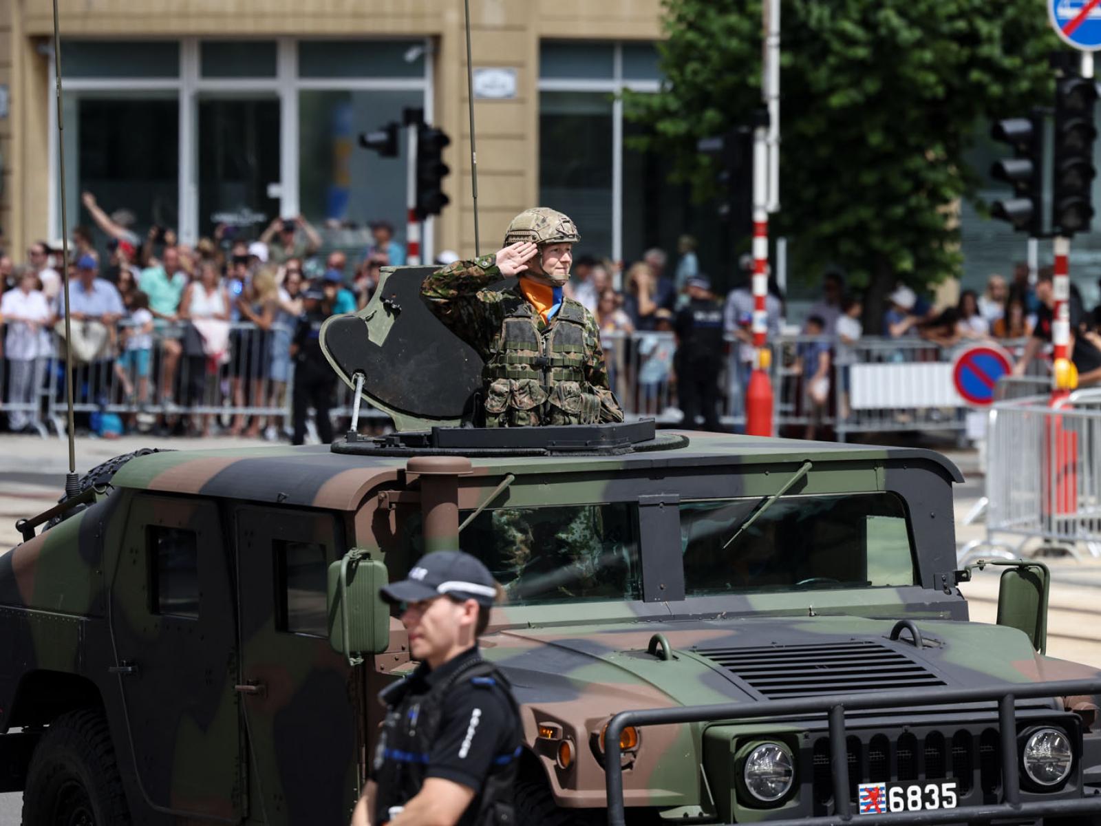 Une militaire salue Leurs Altesses Royales à partir d'un Humvee