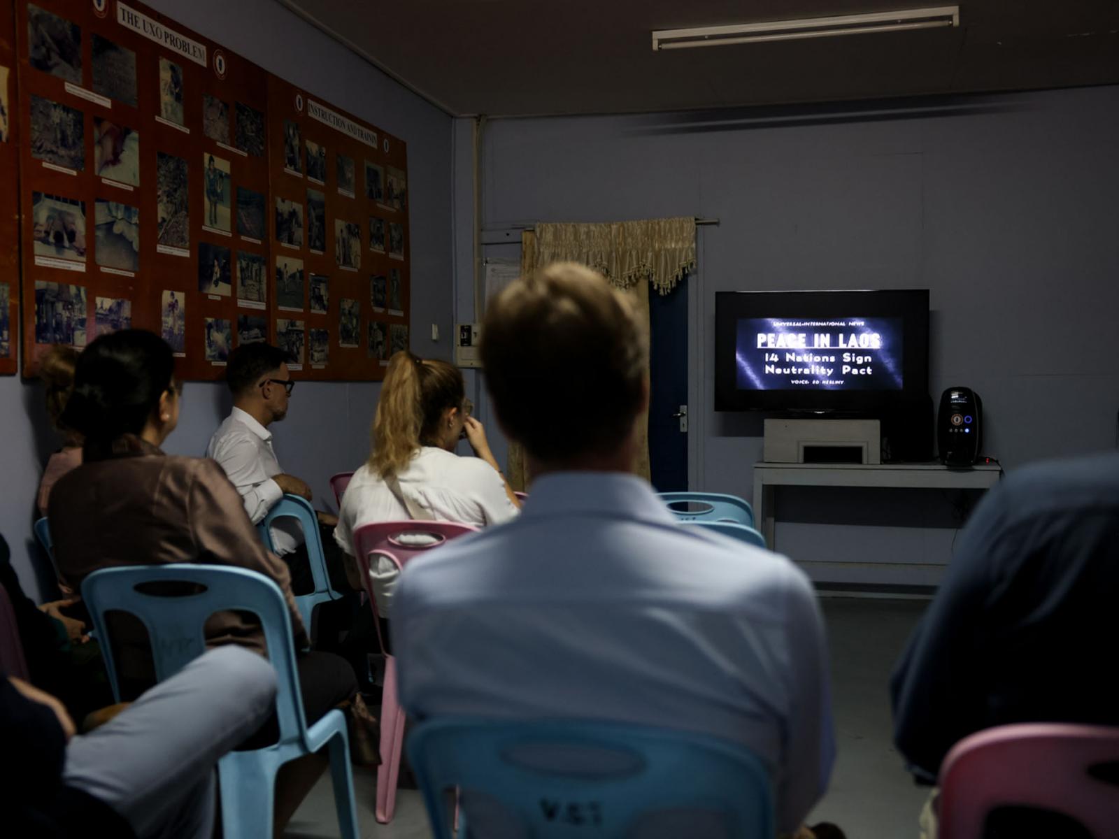Le Grand-Duc et les visiteurs regardent un film sur la guerre au Laos
