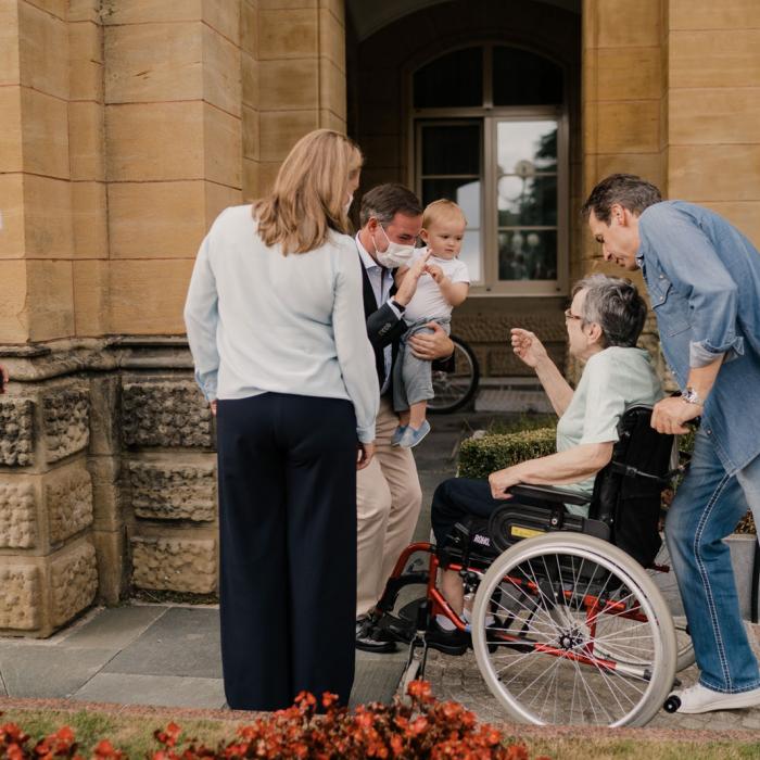 Le Couple héritier et le Prince Charles échange avec une résidente devant la maison de soins