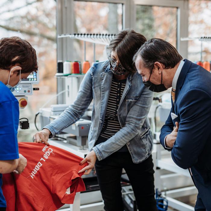 Un membre de l'équipe montre au Prince une broderie sur un vêtement