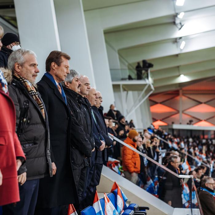 Dans les tribunes, les invités se tiennent debout lors des hymnes