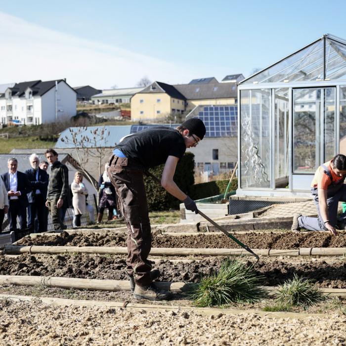 Le Couple héritier découvre le jardin du centre où des jeunes travaillent