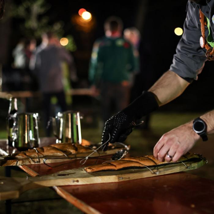 En plein air, un Scout prépare du saumon au feu de bois