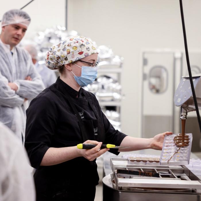 Vue sur une employée en train de remplir des coques de chocolat