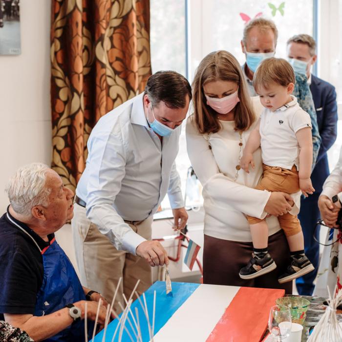 Le Prince peint le drapeau national sous les yeux de la Princesse et de leur fils