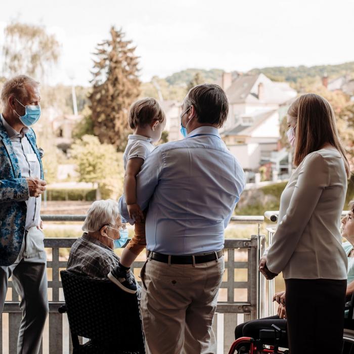 Le Couple héritier et leur fils échangent avec des résidents au balcon de la résidence