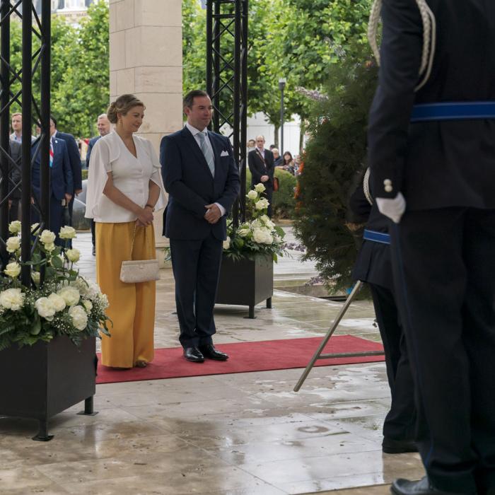 Le Couple héritier devant le monument aux Morts après avoir déposé une gerbe de fleurs