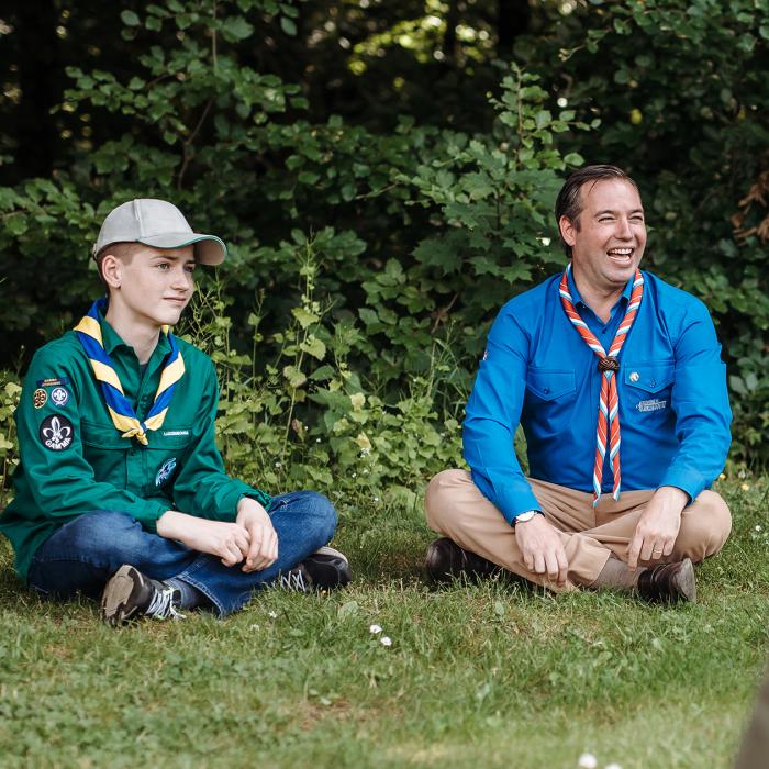 Le Prince Héritier est assis par terre avec un jeune Scout