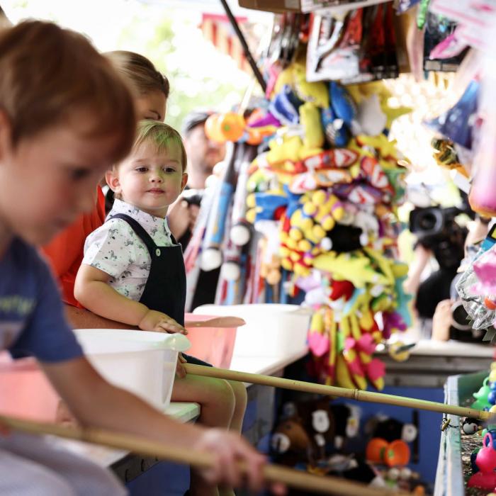 Le Prince Charles observe un autre enfant au stand de la pêche aux canards