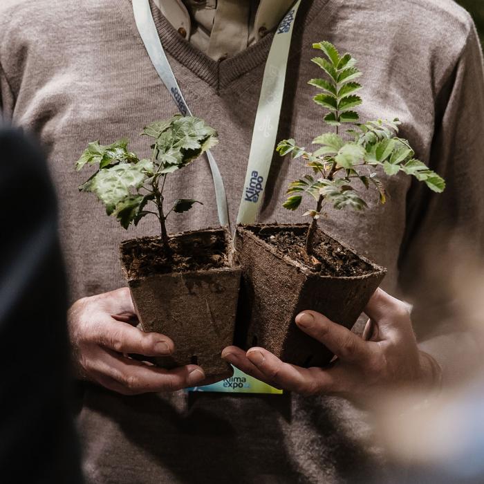 Un exposant tient deux pots de fleurs