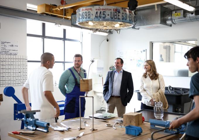 Le Couple héritier échange avec un jeune dans l'atelier menuiserie